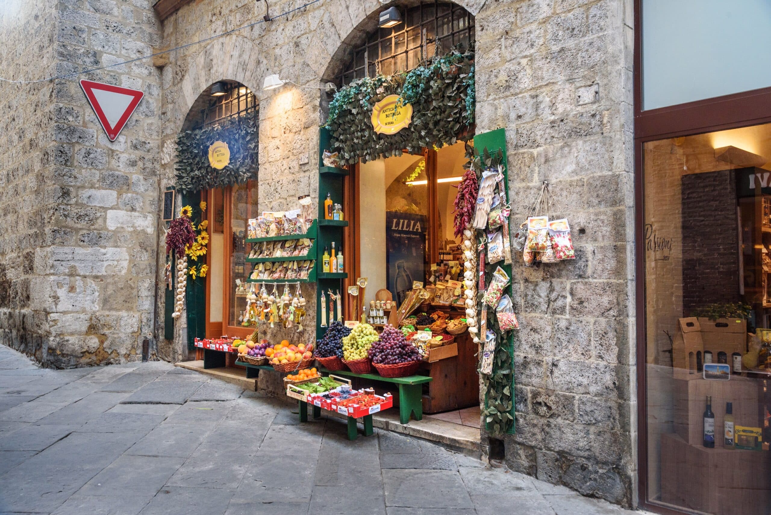 Siena, Italy - October 06, 2018: Local shop for selling fruits, vegetables, cheese and other local products on the medieval narrow street in Siena