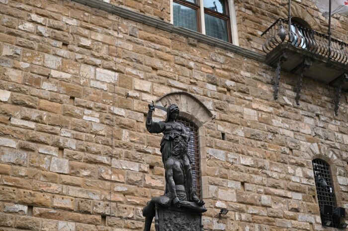 a large stone statue in front of a brick building