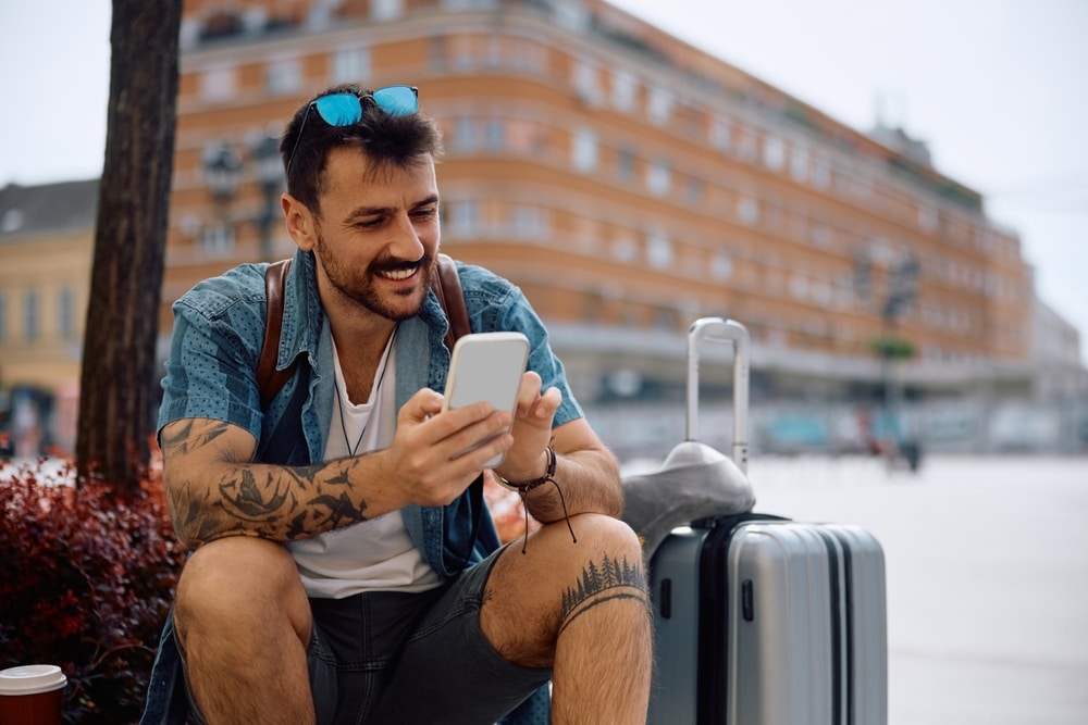 A traveler looking at his phone and browsing for essential mobile apps