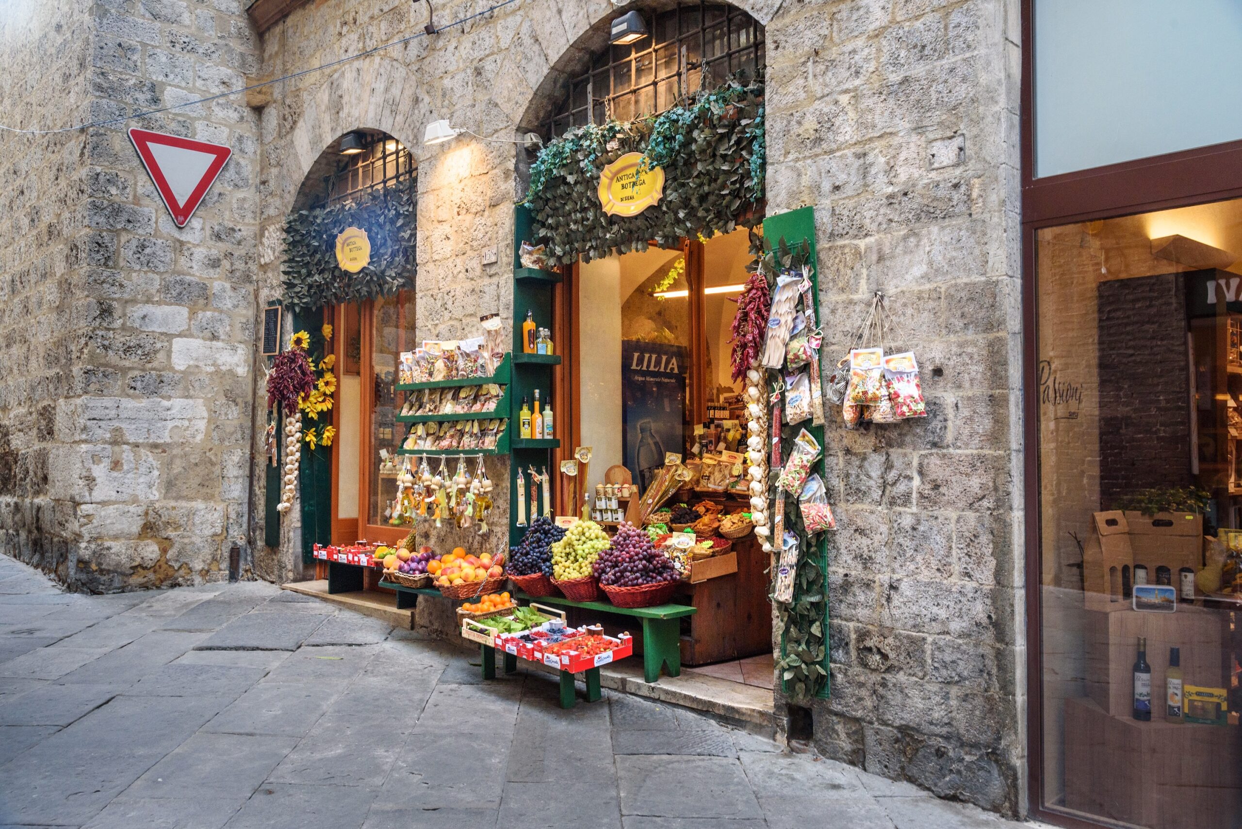 Siena street scene — local food shop with fresh produce in the medieval streets of Siena, Italy