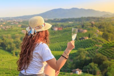 Traveler enjoying a glass of Prosecco above the vineyards of Valdobbiadene