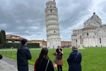 a group of people standing in front of a castle with Leaning Tower of Pisa in the background